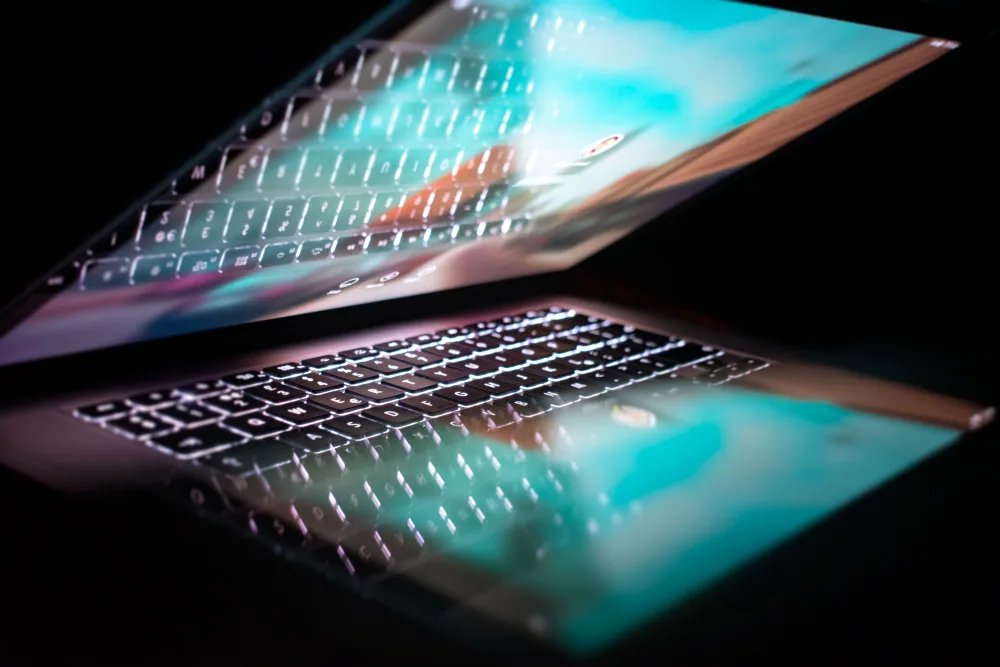 A multi-colored glassy laptop halfway open on a black background.